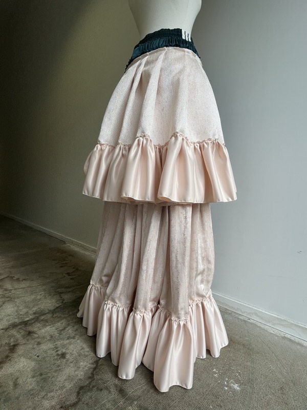 A two-tier blush skirt on a dress form: ivory waffle cloth above a deep peach satin ruffle, over pale pink panne velvet.